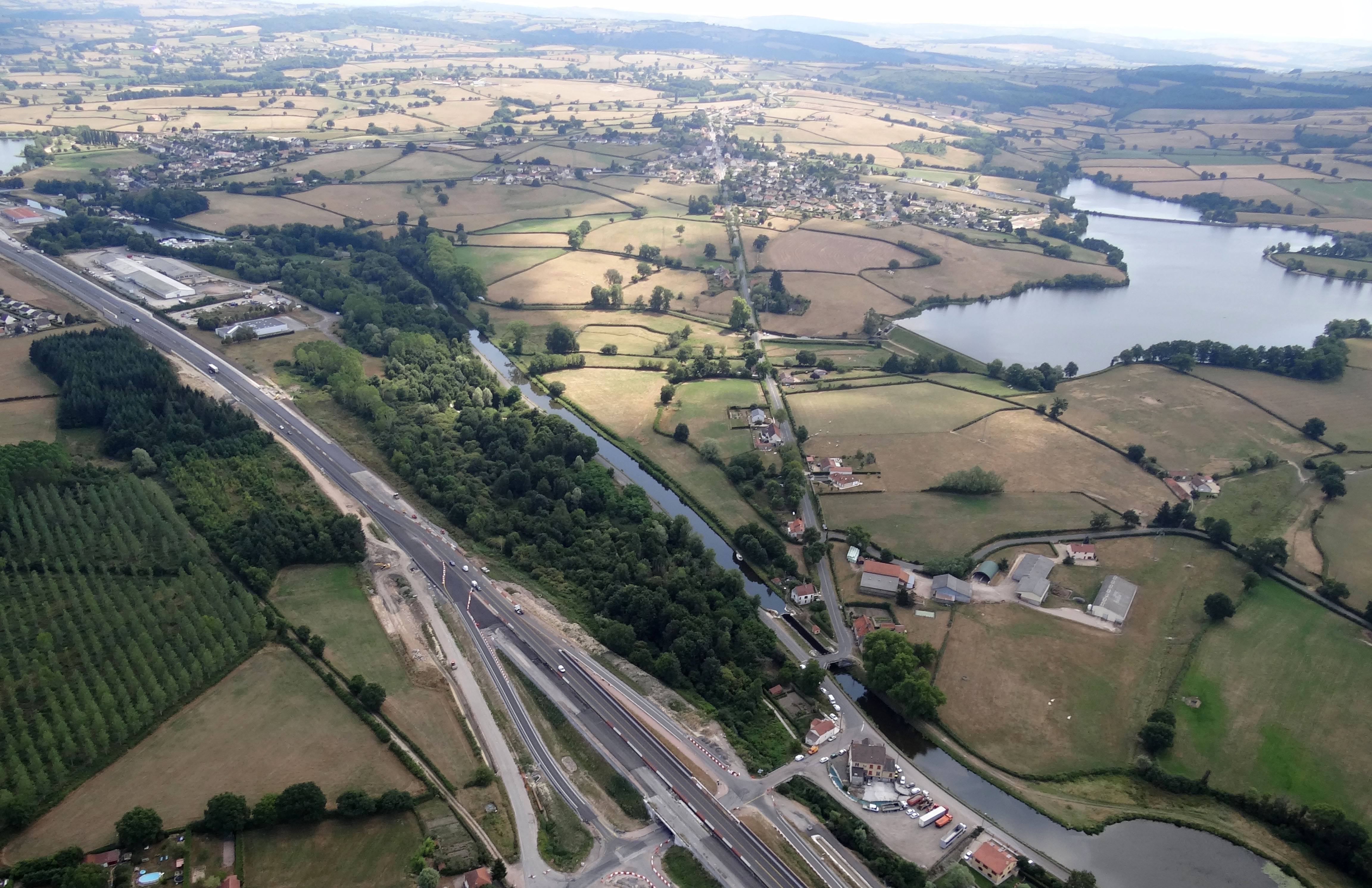 Le canal du Centre assure la liaison entre la Saône et la Loire, en empruntant successivement les vallées de la Dheune et de la Bourbince. Il franchit la crête entre ces deux allées au seuil de Longpendu, à hauteur de Montchanin. Il est alimenté par plusieurs barrages réservoirs. Au premier plan on peut noter la concentration d’infrastructures sur un faible espace avec la RN70 , la Bourbince ici très près de sa source qui circule enfouie sous une épaisse ripisylve, le canal du Centre et l’écluse des Brenots, longés par la RD 974 qui emprunte la berge. Au second plan l’étang Berthaud fait partie des huit barrages réservoir qui alimentent le canal. Montchanin et St-Eusèbe