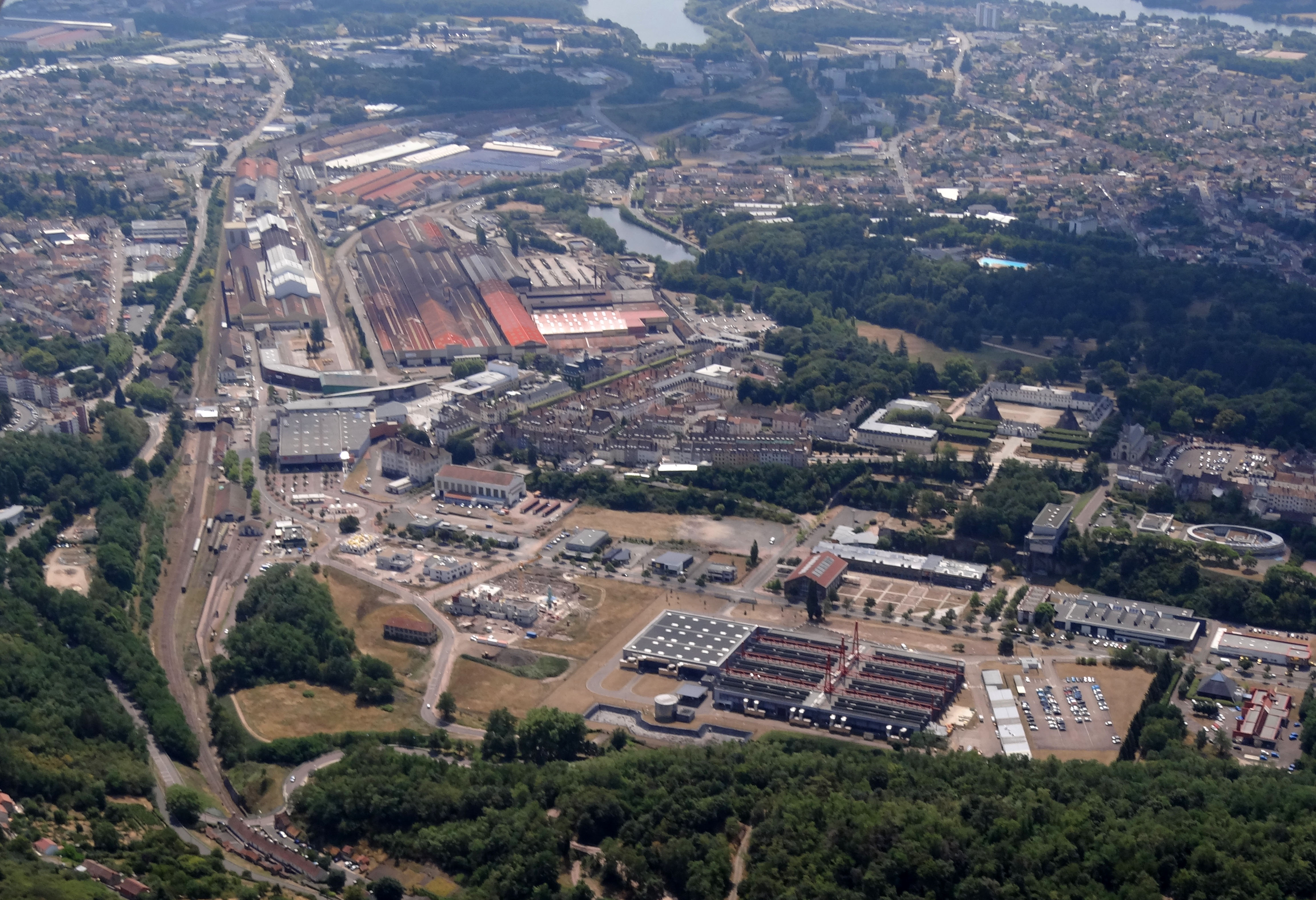 Autour des pôles du Creusot (22 000 hab) et de Montceau-les-Mines (19 000 hab), le Bassin Minier présente un territoire fortement urbanisé. Le passé minier et industriel explique le tissu urbain atypique de ce territoire. Les villes se sont étendues autour des sites industriels ou miniers avec de vastes opérations de logements. Ici les forges du Creusot sont implantées au cœur de la ville. De part et d’autre, sous l’impulsion des Schneider, maitres des forges, s’est développé une ville nouvelle qui atteindra jusqu’à 34000 habitants à son apogée dans les années 1970. A gauche l'ancienne cristallerie royale, transformée en résidence familiale par les Schneider rebaptisée le château de la Verrerie.