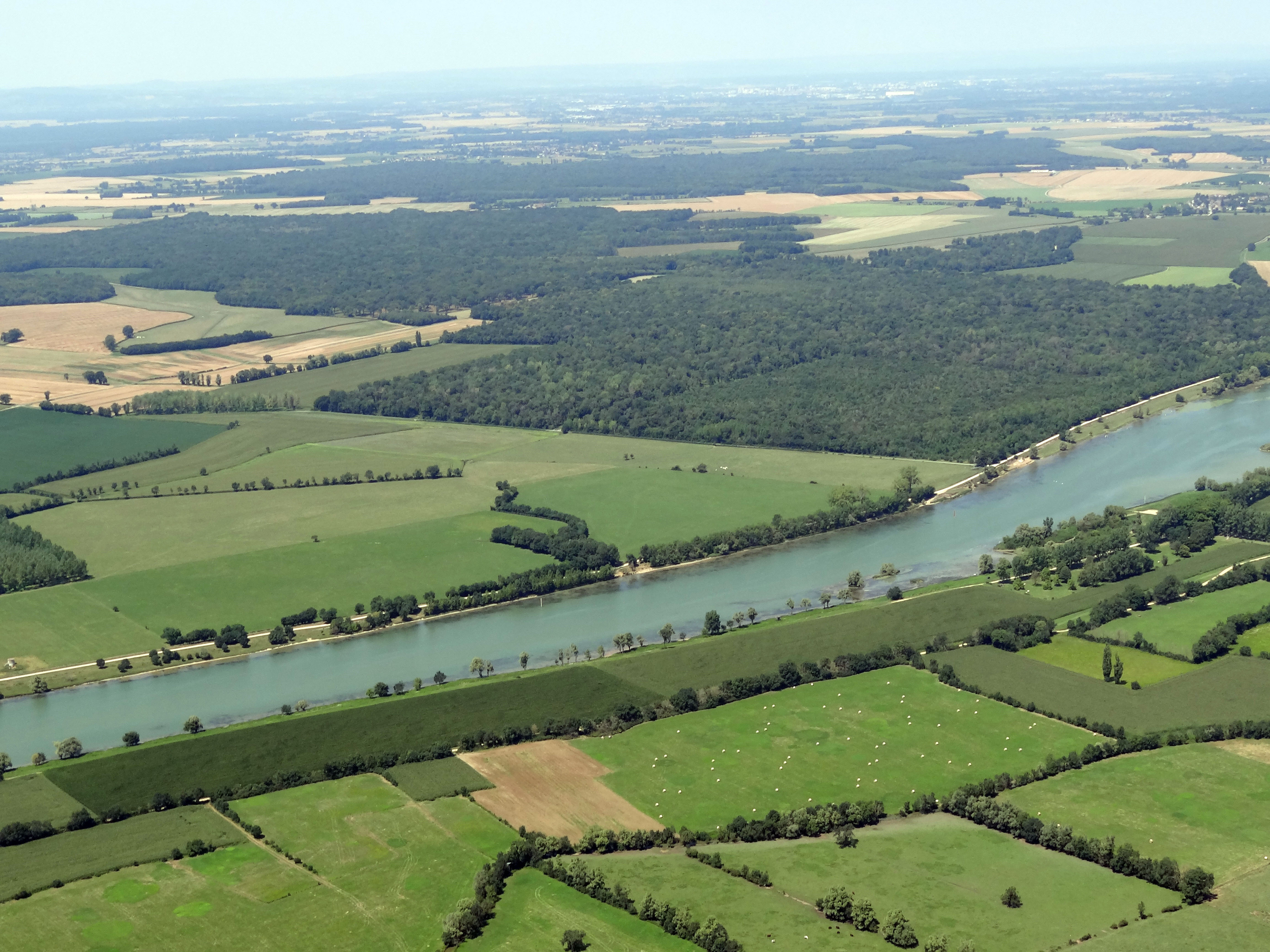 Les prairies bocagères occupent l’essentiel du fond de vallée (ici au premier plan) alors que sur la terrasse (en arrière-plan) les cultures dominent, formant de vastes enclaves agricoles à grandes parcelles entre les massifs forestiers. En second plan le bois de Voivre sur la commune de Boyer. Vue vers le nord-ouest