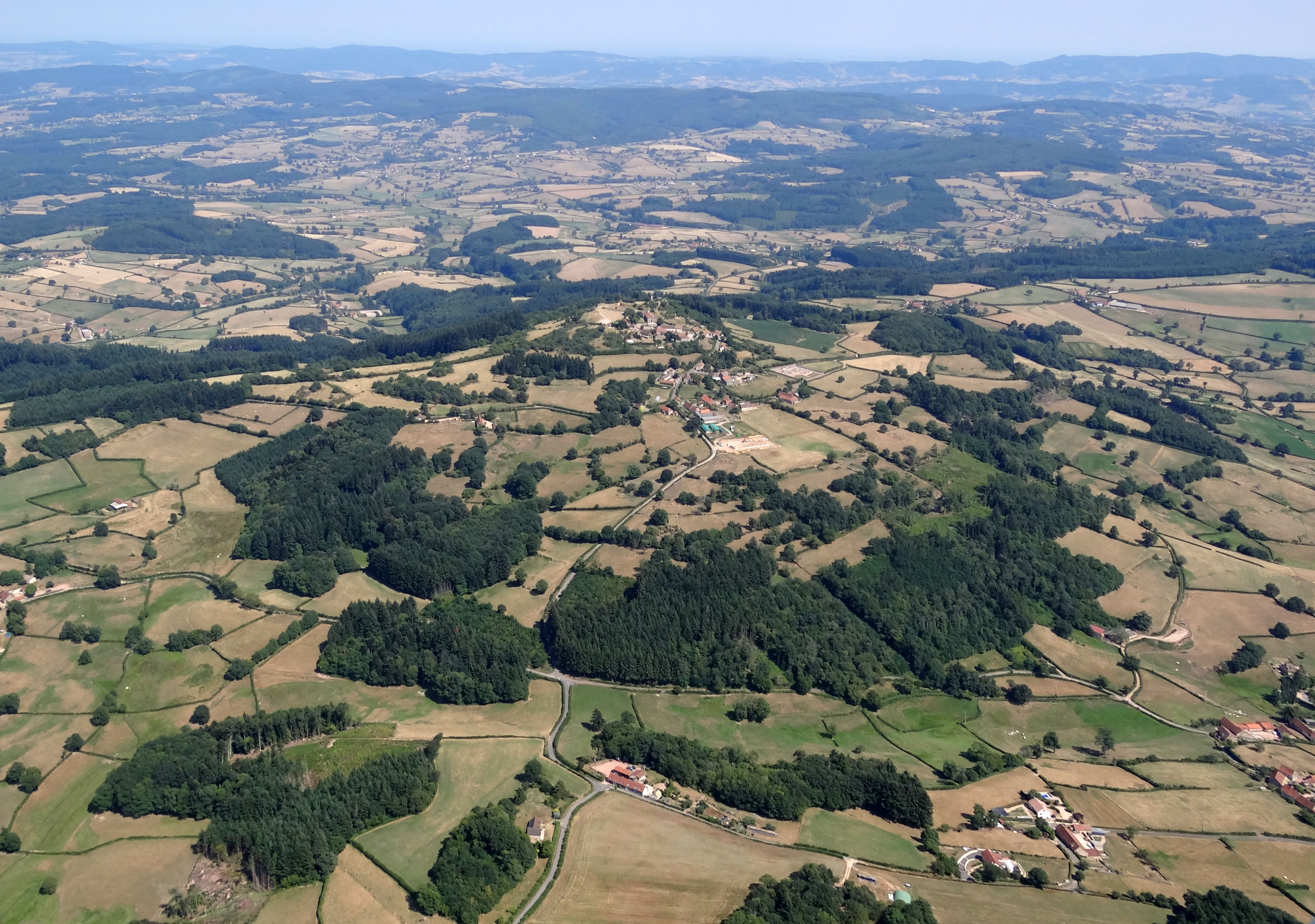 A l’est dominent les roches granitiques. On y retrouve tous les sols classiques sur granite depuis les sols maigres des crêtes boisées, les sols d’arène plus épais des collines bocagères, les fonds humides argileux accumulés au fond des vallées en U. Sur ces roches dures des buttes élevées se distinguent : butte de Suin 600 m, mont St-Cyr 771 m, montagne de Dun 721 m. Les sommets de ces buttes offrent des vues panoramiques sur le Charolais, le Brionnais, la vallée de la Loire, le Mâconnais et le Beaujolais et par temps clair, au-delà, vers les monts de la Madeleine et ceux du Lyonnais. La butte et le village de Suin, au premier-plan le hameau des Falattes