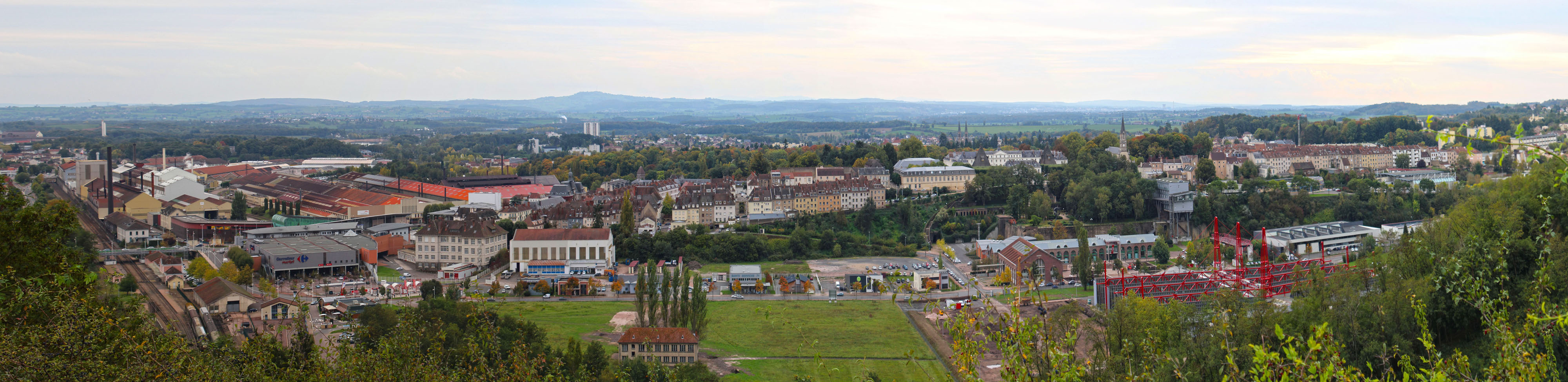 La ville du Creusot, construite autour des forges et des voies ferrées, est adossée aux versants de la Montagne Autunoise. Panorama de la plaine des Riaux